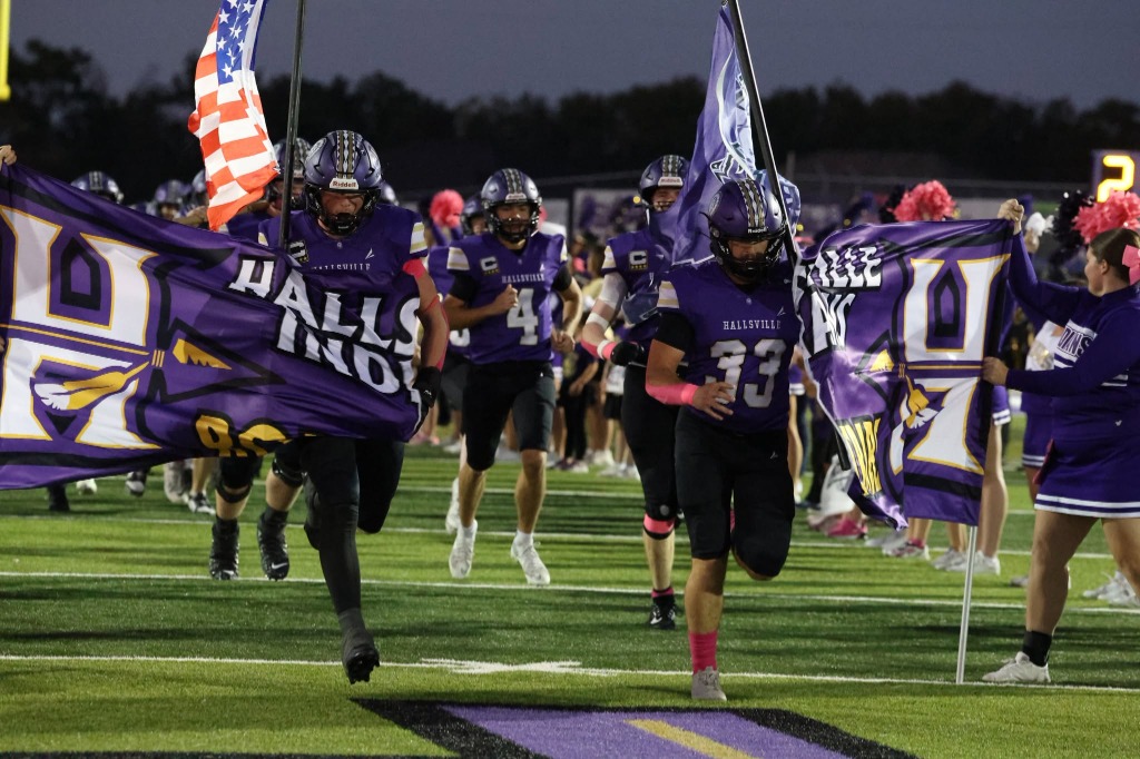 Hallsville Indians football team running onto the field with flags